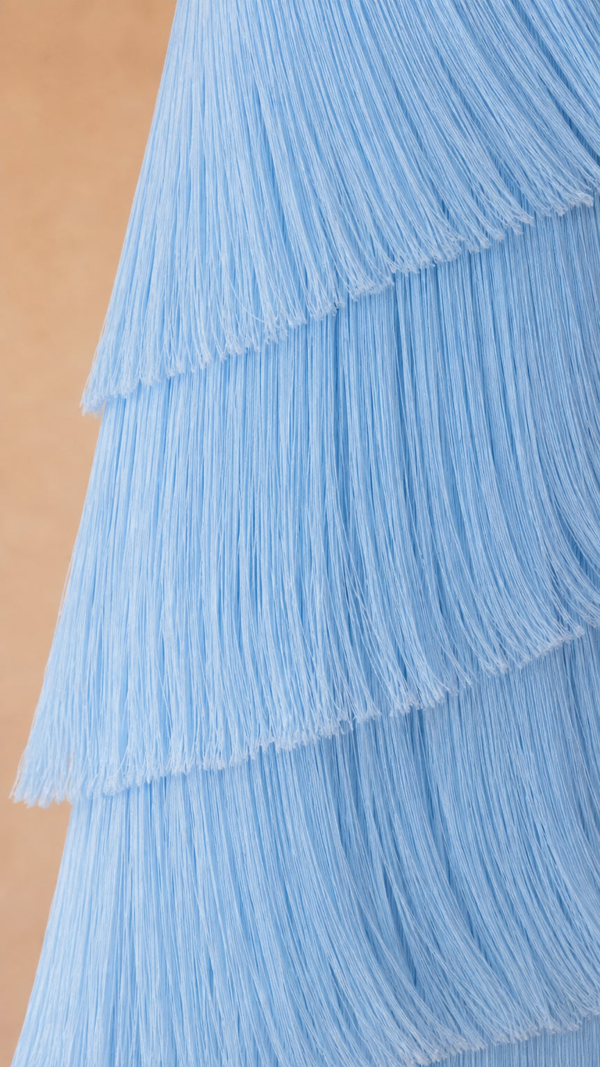 Close-up detail of textured sky blue fringe layers on strapless maxi gown