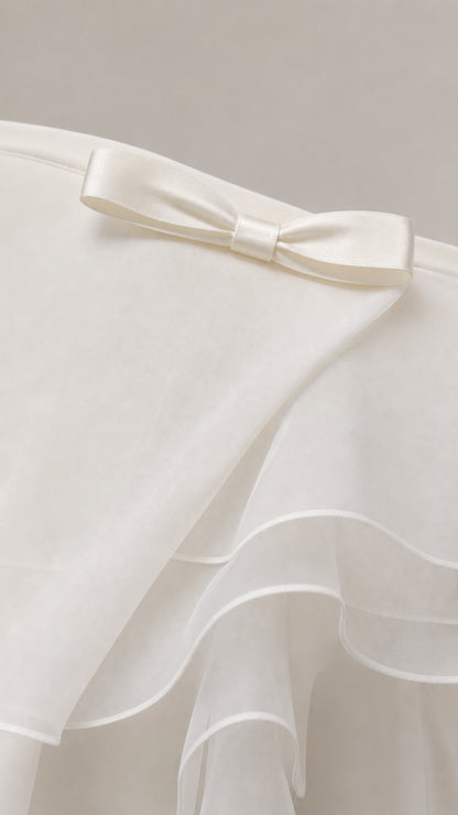Close-up of front bow detail and layered fabric on white dress