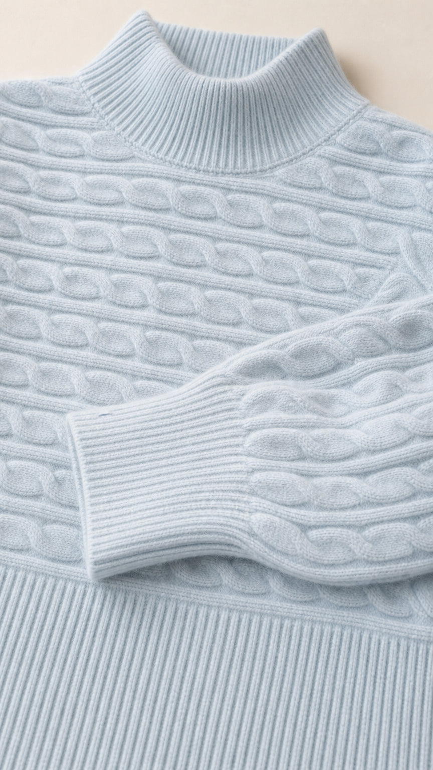 Close-up detail of light blue mock neck sweater showing cable knit texture and ribbed collar and cuffs