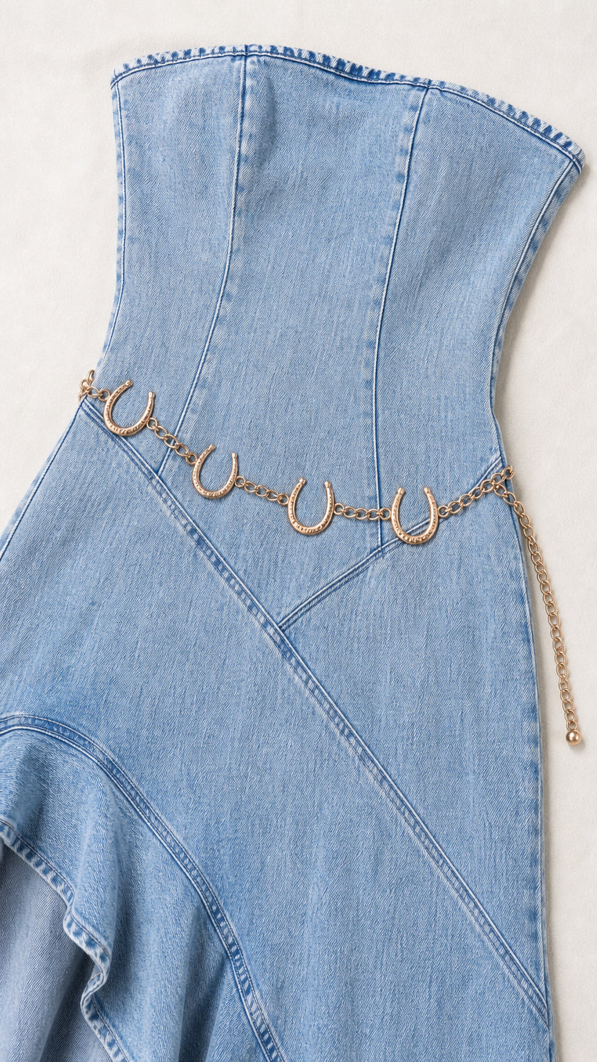 Close-up flat lay view of light blue denim bodice and chain belt