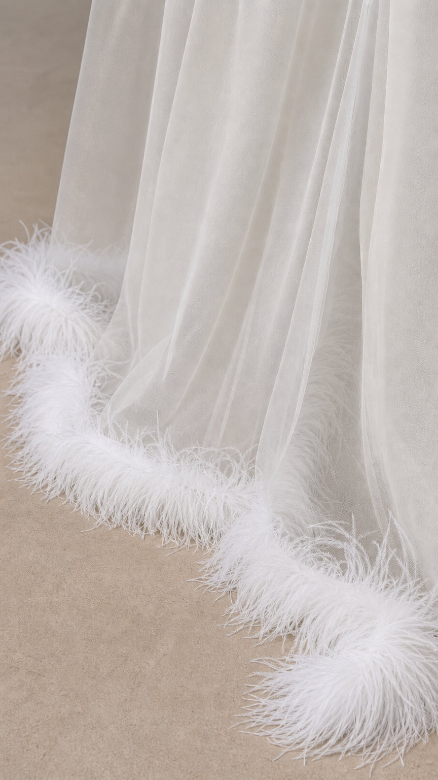 Close up view of sheer white tulle fabric and plush feather hem