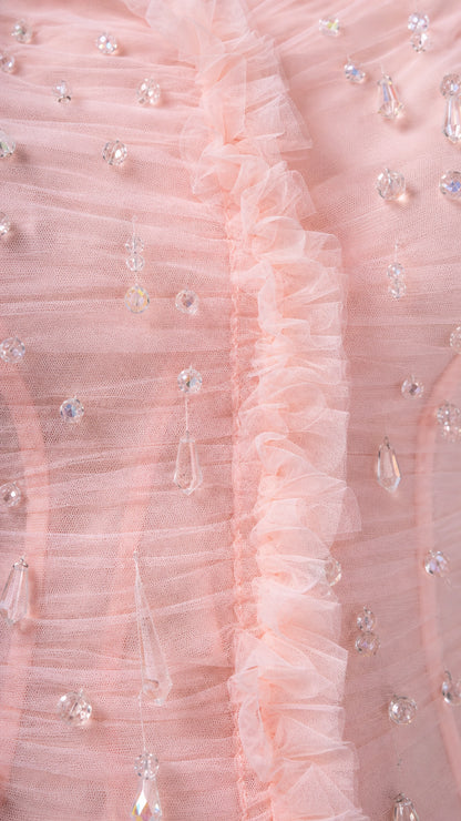 Close-up of textured blush pink mesh, ruffles, and crystal-style embellishments