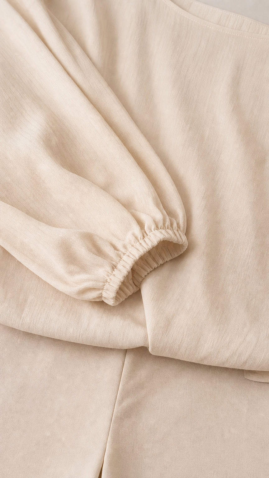 Close-up of fabric texture and elastic sleeve cuff on beige set