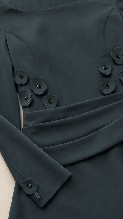 Close-up detail of floral appliques and cuff buttons on dark teal dress