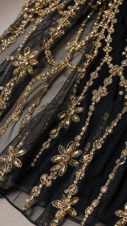 Close-up detail of gold metallic beadwork on black mesh fabric