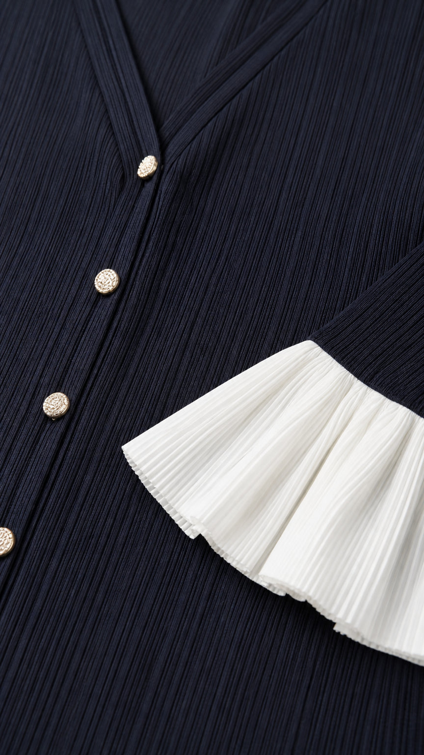 Close-up detail of button placket and pleated white cuffs on navy dress