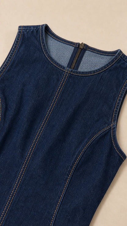 Close-up of sleeveless neckline and contrast stitching on dark blue denim dress