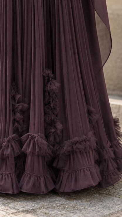 Close-up detail of ruffled hem and pleats on plum maxi dress