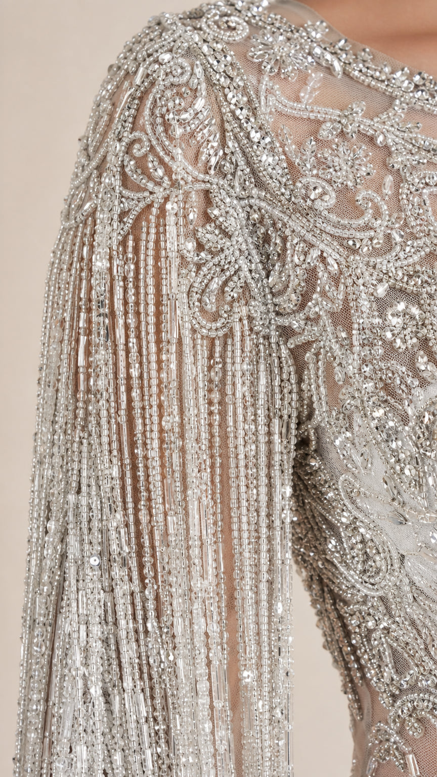 Close-up detail of silver sequin embroidery, beadwork, and tassel fringe sleeve