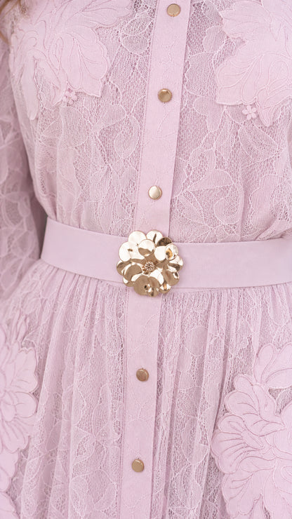Close-up detail of blush pink lace fabric, front buttons, and gold floral belt buckle