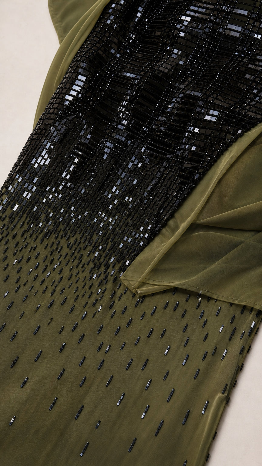 Close-up detail of linear black bead and sequin embellishment fading into olive fabric