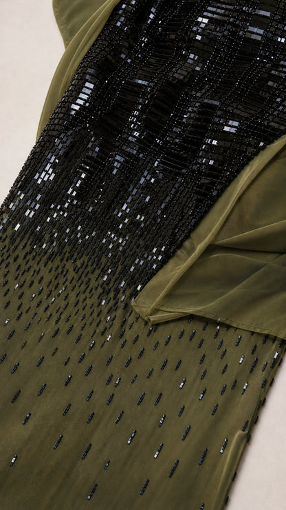 Close-up detail of linear black bead and sequin embellishment fading into olive fabric