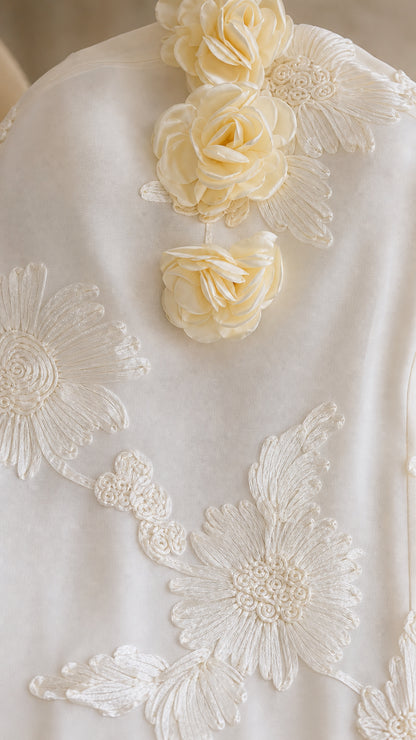 Close-up detail of 3D rosettes and intricate floral lace embroidery on dress