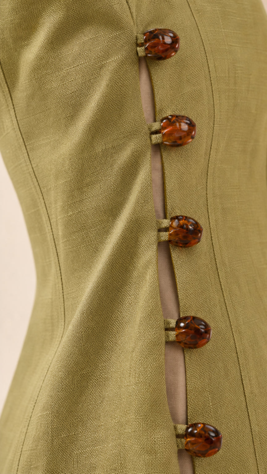 Close-up detail of tortoise-shell buttons on the side of the green dress
