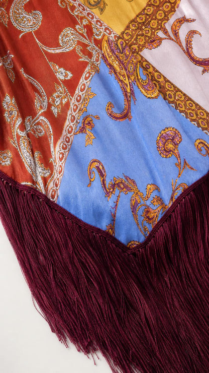 Close-up detail shot of the paisley fabric pattern and burgundy fringe hem