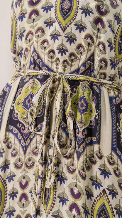 Close-up detail of self-tie waist and intricate pattern on cream dress