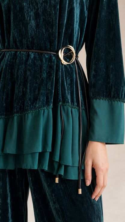 Close-up detail of tiered ruffle hem, belt buckle, and textured velvet fabric in dark green