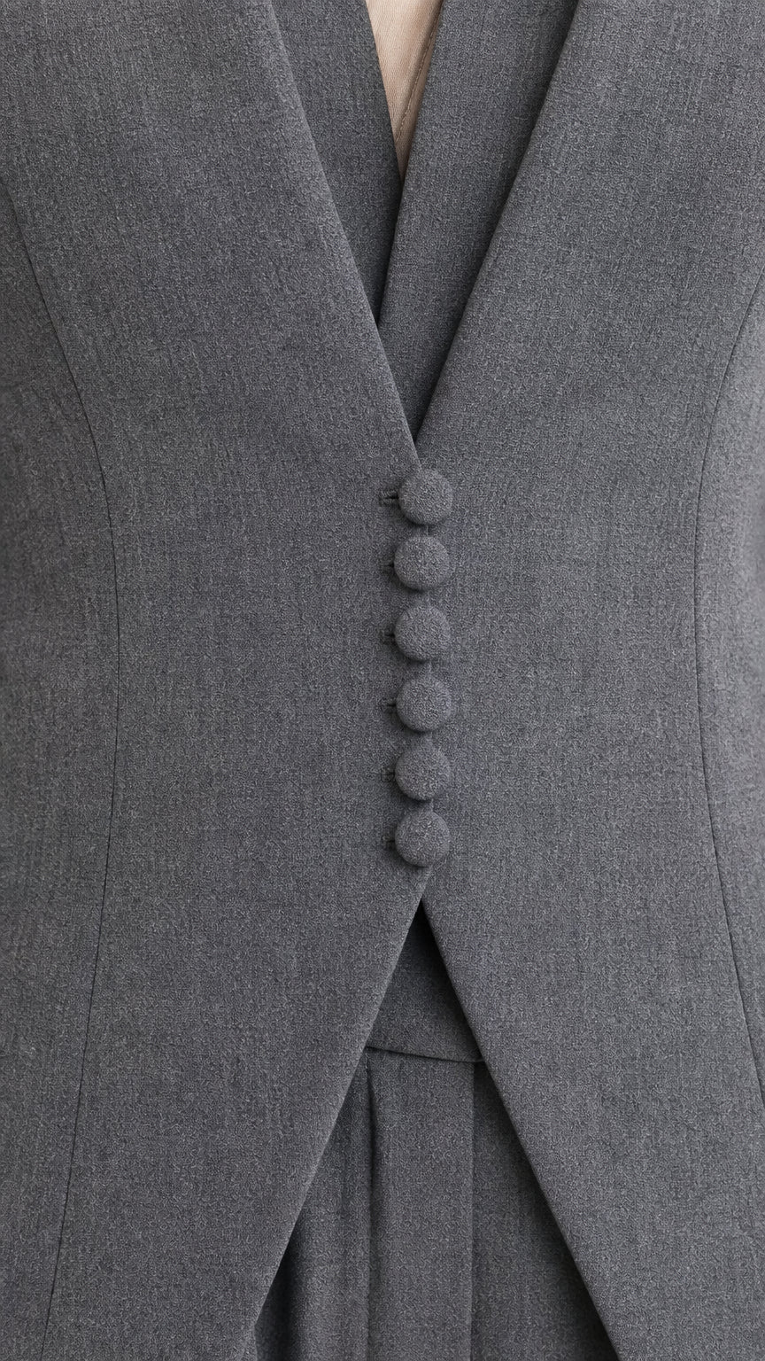 Close-up detail of grey blazer showcasing tonal covered buttons and elegant lapel tailoring
