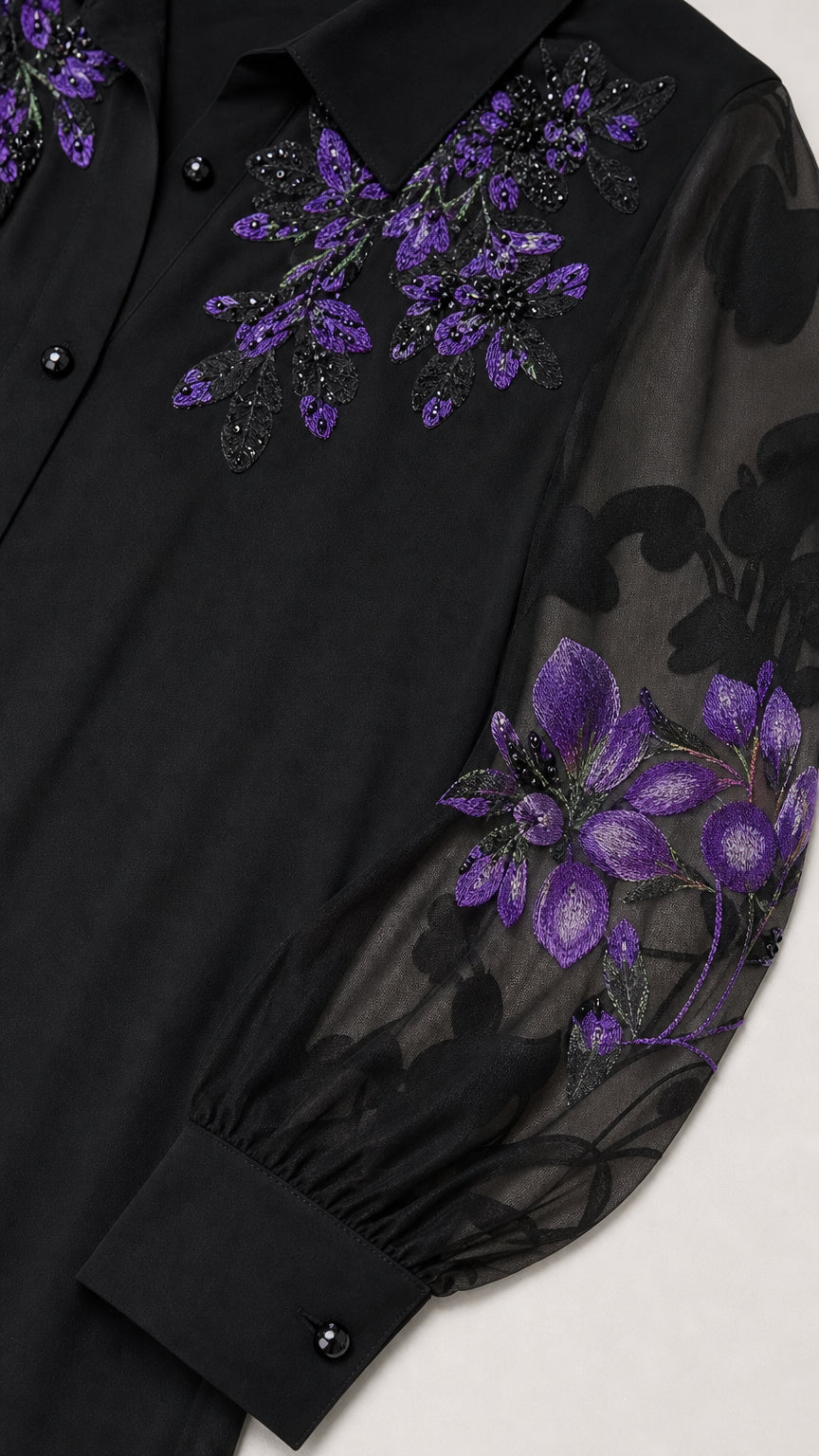 Close-up detail of collar and embroidered sheer sleeve on black dress