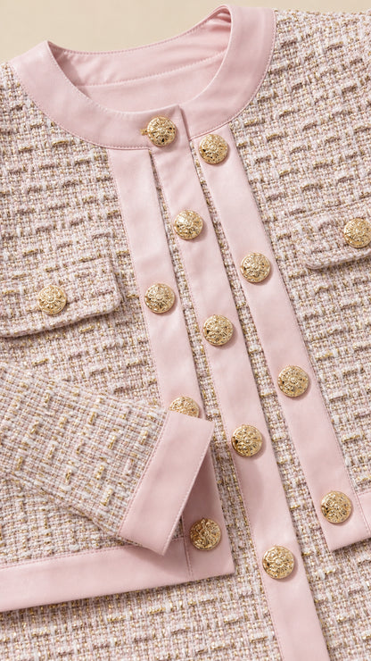 Close-up detail of pink tweed jacket showing metallic buttons and contrast piping