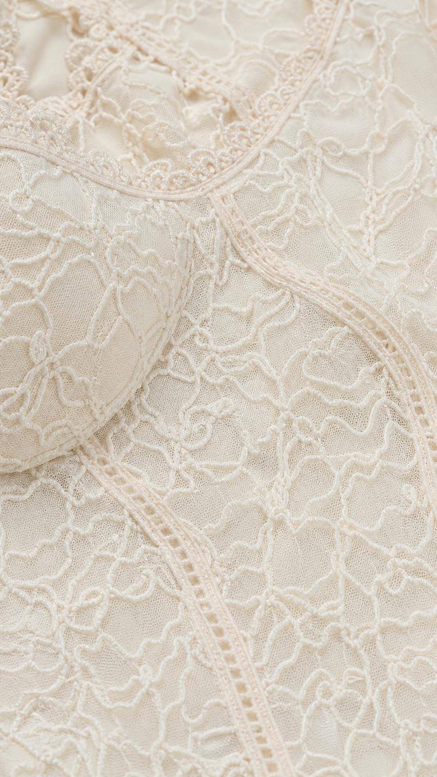 Close-up detail of textured lace fabric and scoop neckline
