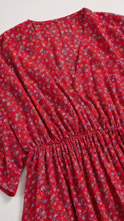 Close-up detail of red ditsy floral print, gathered elastic waist, and V-neckline