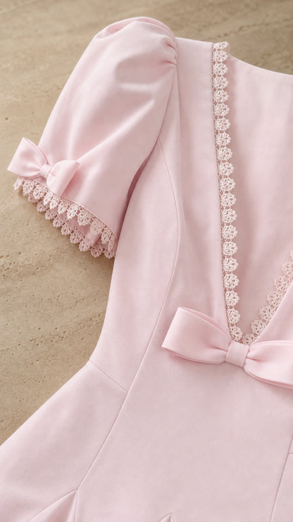 Close-up detail of puff sleeve, lace trim, and bow on pink dress