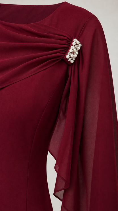 Close-up of pleated bodice and pearl brooch detail on burgundy dress