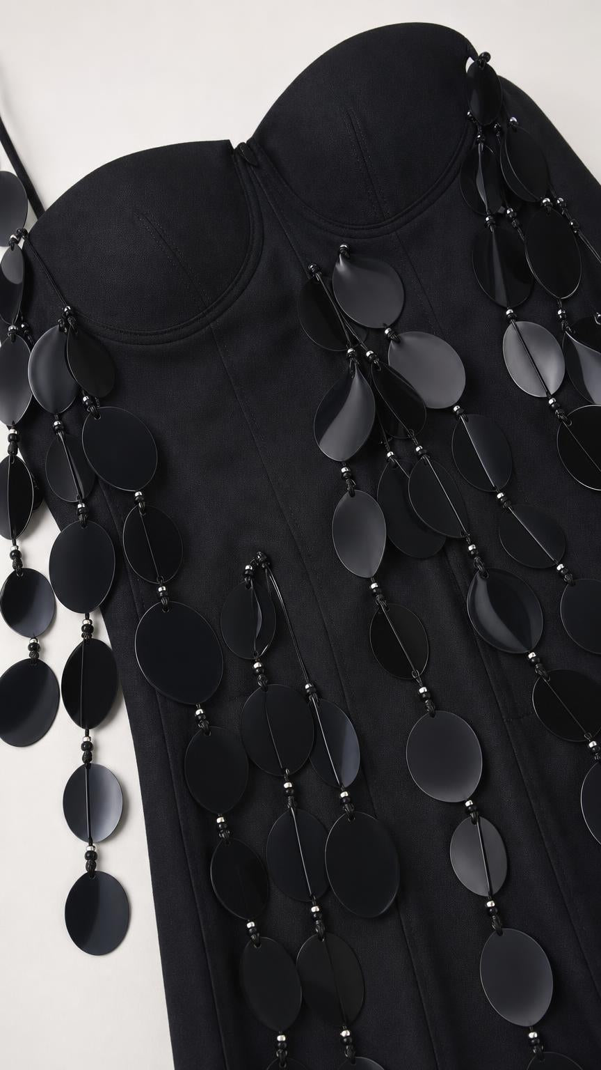 Close-up of fabric and hanging disc embellishments on black dress