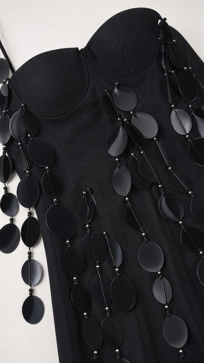 Close-up of fabric and hanging disc embellishments on black dress