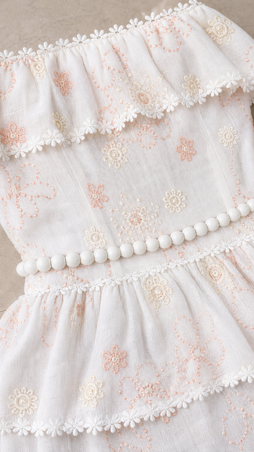 Close-up detail of ruffle bodice, pom-pom trim, and floral embroidery