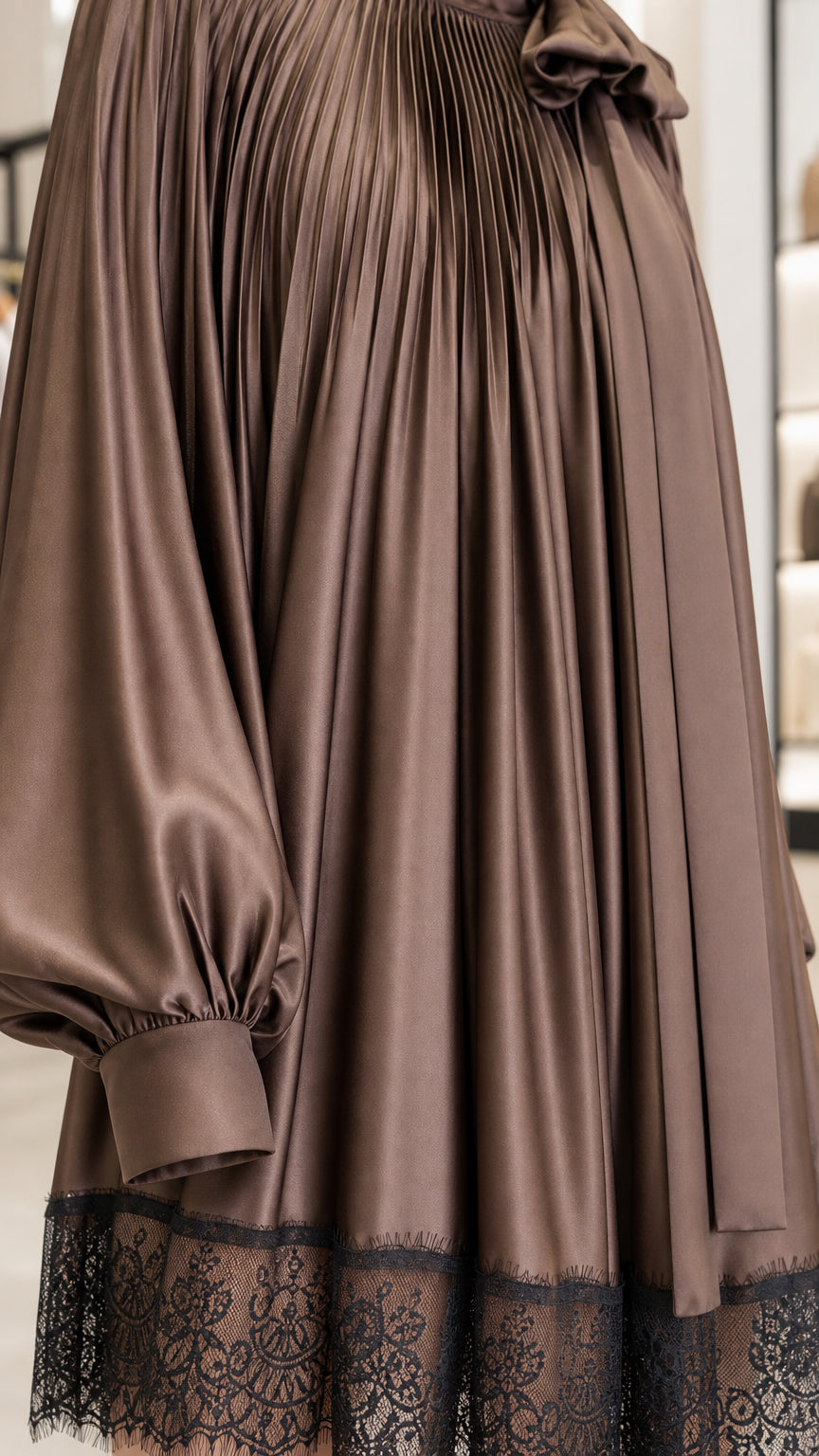 Close-up detail of satin fabric, pleats, and lace hem