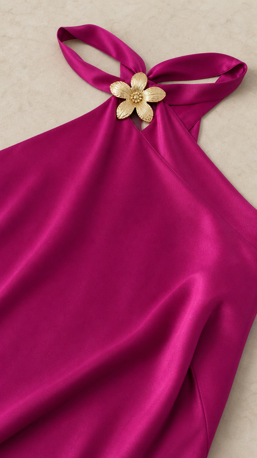 Close-up of gold floral hardware detail on fuchsia satin halter neckline
