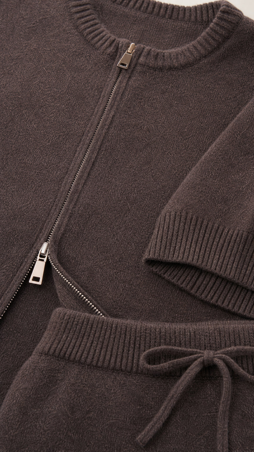 Close-up detail of taupe knit texture, front zipper, ribbed neckline, and drawstring waist