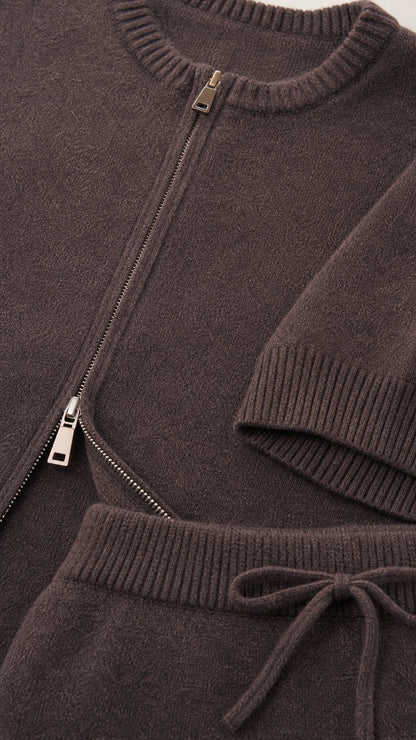 Close-up detail of taupe knit texture, front zipper, ribbed neckline, and drawstring waist