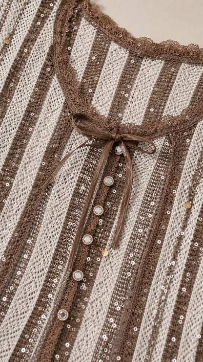Close-up detail of the lace-trimmed neckline, ribbon tie, buttons, and sequined stripes