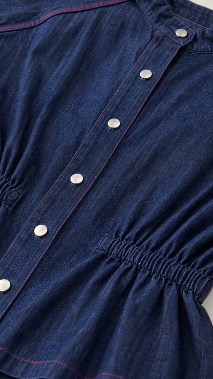 Close-up detail of dark blue denim top with buttons and elastic waist