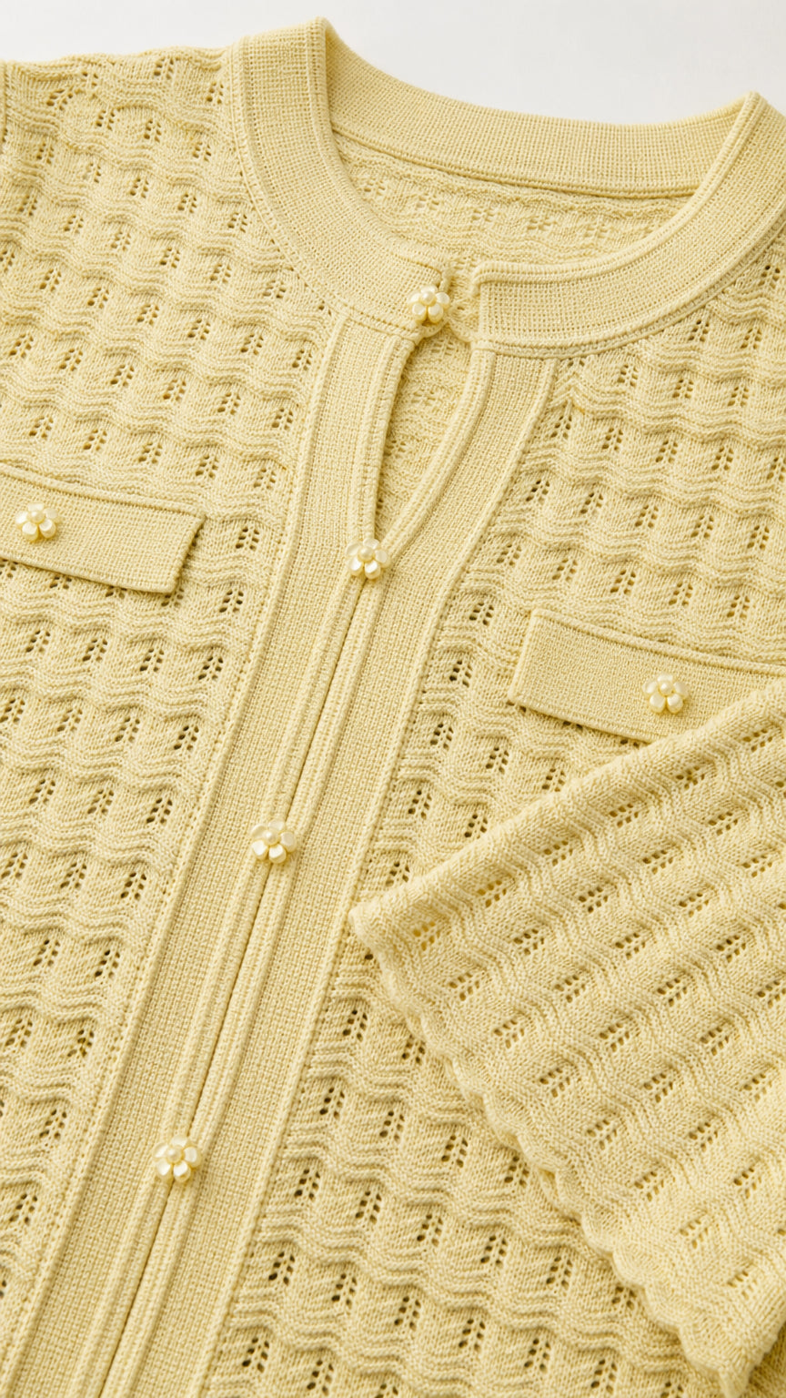 Close-up detail of yellow knit pattern, buttons, and collar