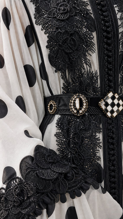 Close-up detail of ornate black lace trim, neckline embroidery, and jeweled belt buckle