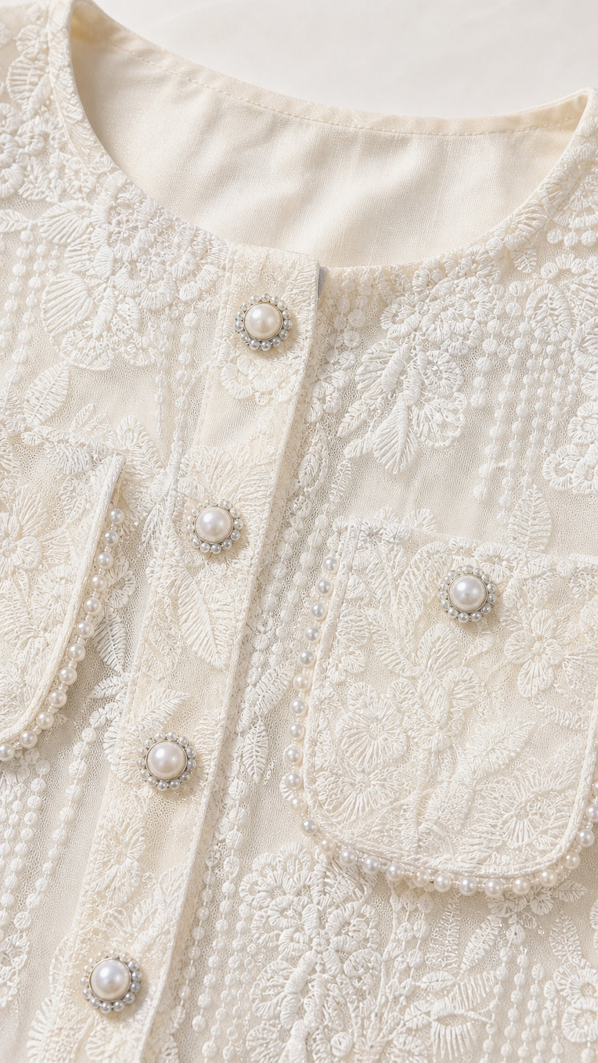 Close-up detail of pearl buttons and lace embroidery on white jacket