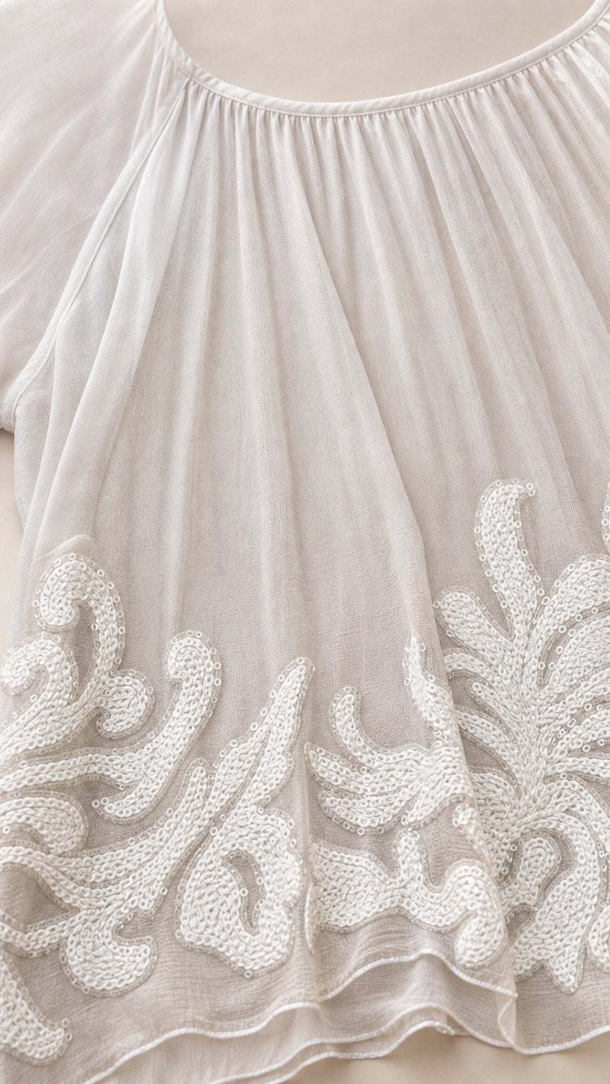 Close up view of intricate white corded embroidery on chiffon hemline
