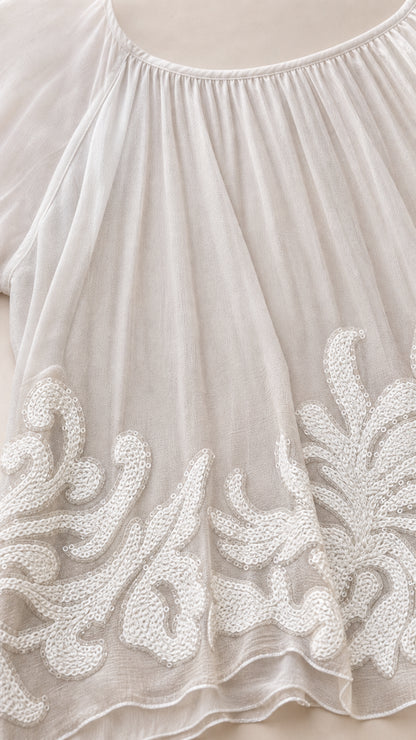 Close up view of intricate white corded embroidery on chiffon hemline