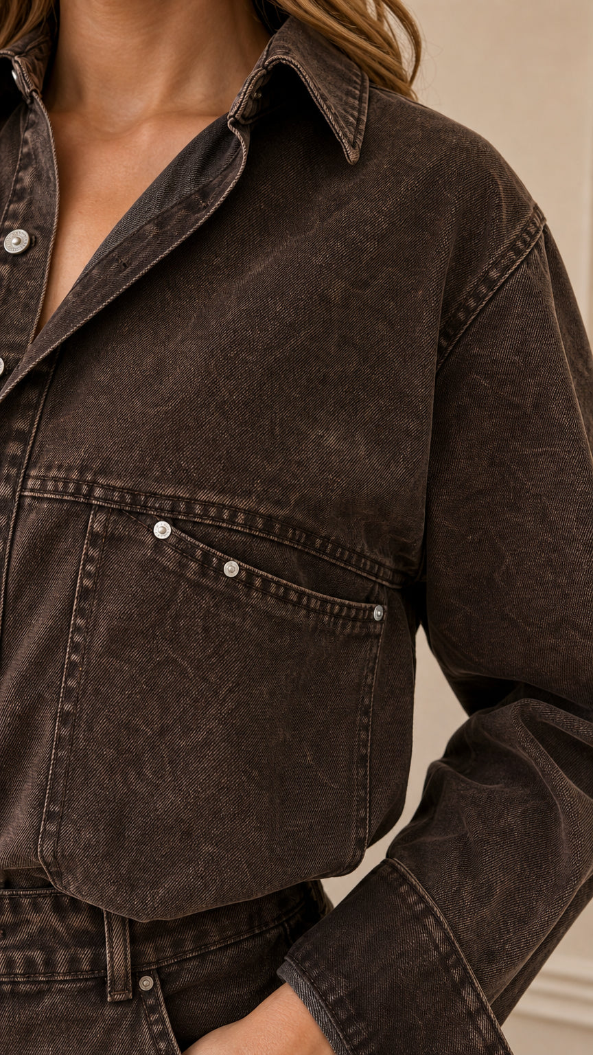 Close-up detail of chest pocket with metal rivets and collar on brown denim jumpsuit