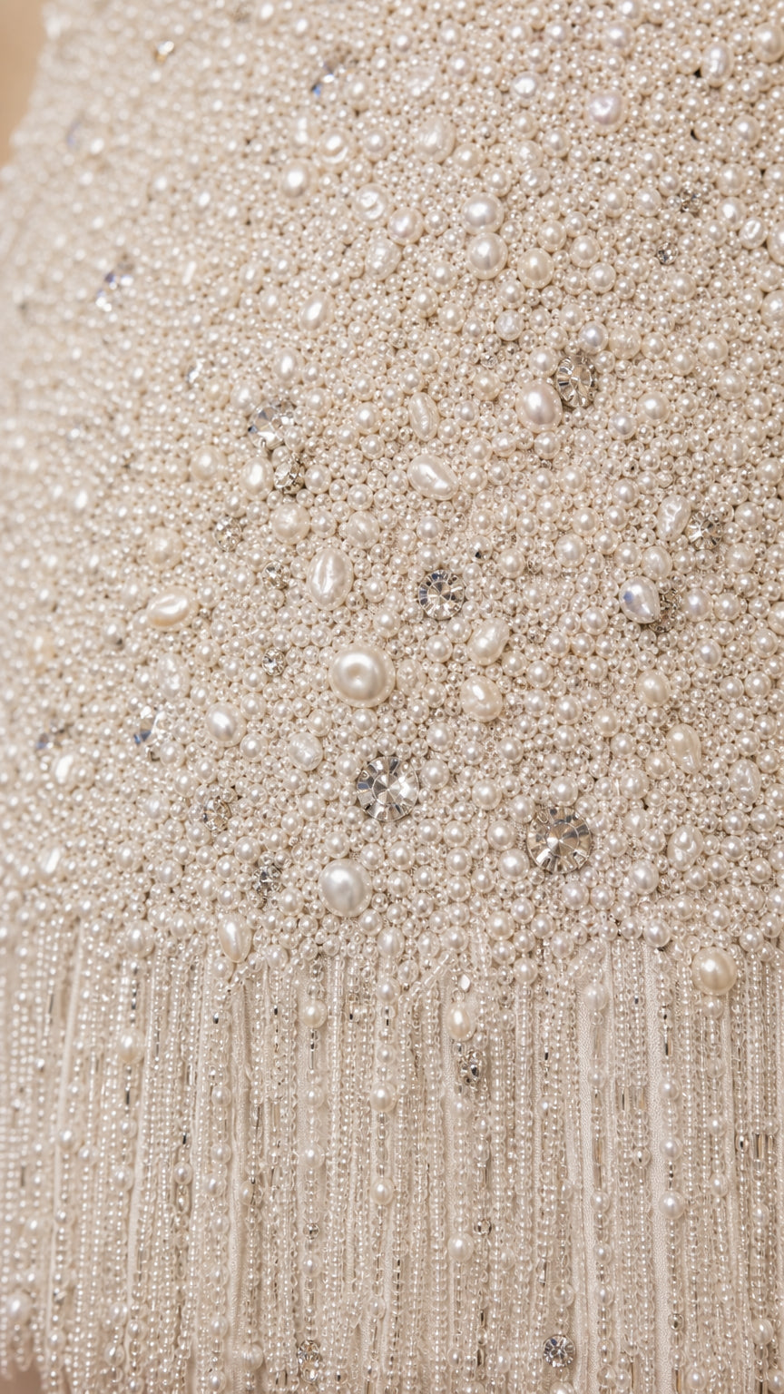 Close-up detail of beads, pearls, and fringe hem