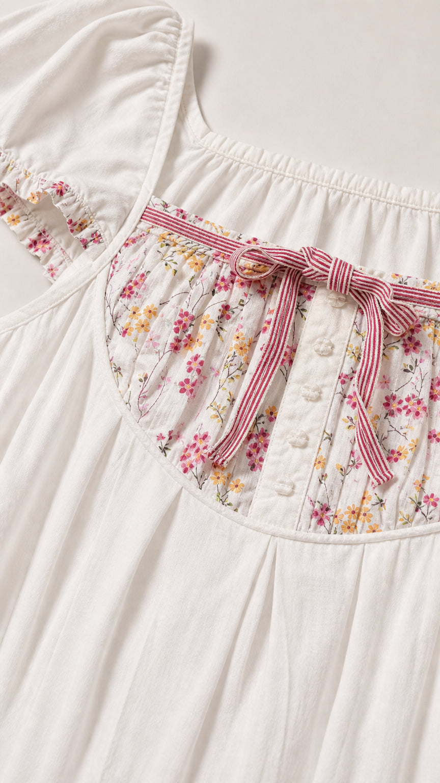 Close up of floral yoke bodice, ribbon bow, and button detail