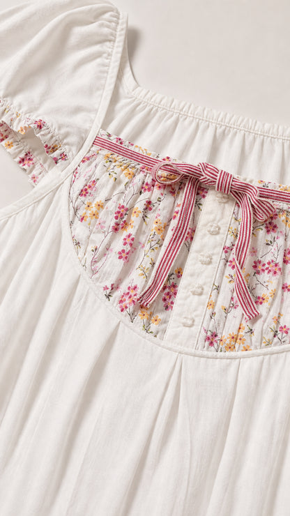Close up of floral yoke bodice, ribbon bow, and button detail