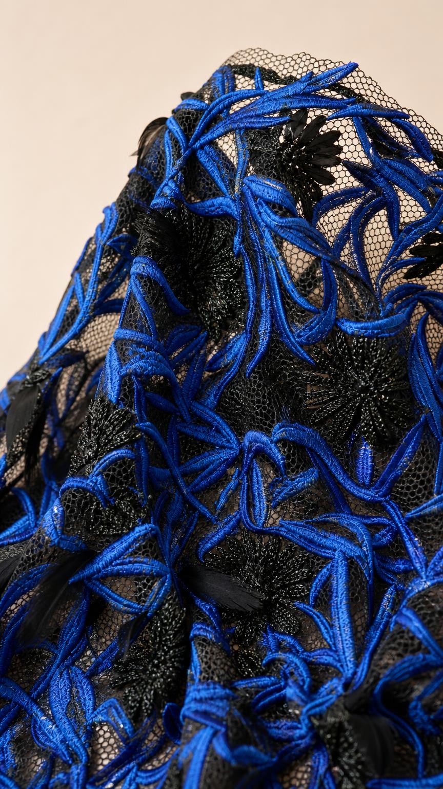 Close up fabric detail of royal blue and black embroidery on mesh