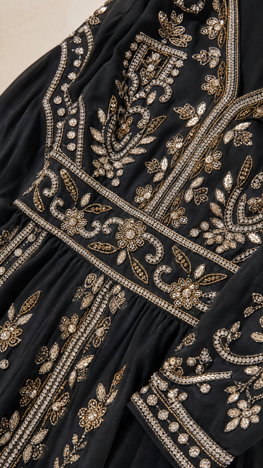 Close-up detail of intricate gold sequin and bead embroidery on black fabric