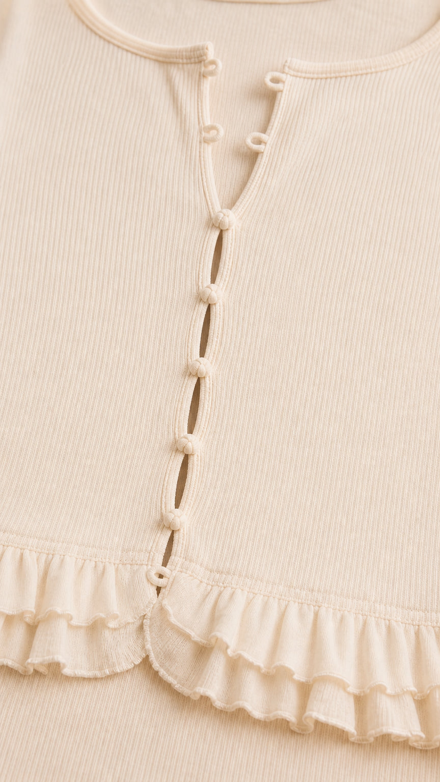 Close-up of cream ribbed button-front bodice with ruffled peplum hem