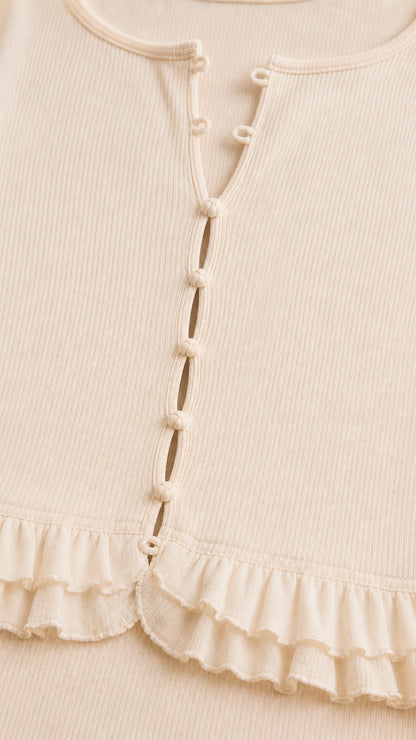Close-up of cream ribbed button-front bodice with ruffled peplum hem